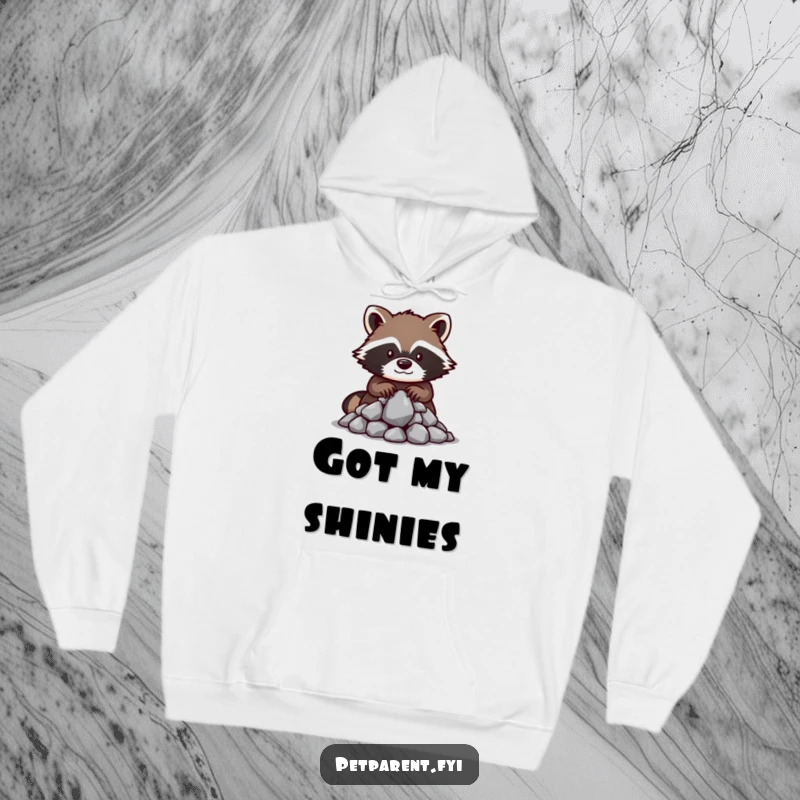 Funny raccoon hoodie depicting a protective raccoon character guarding a pile of shiny, glittering rocks, offering warmth and humor.